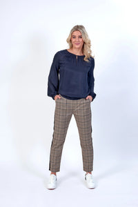 Woman wearing navy long sleeve blouse with checked trousers and white sneakers
