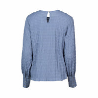 Back view of a textured denim blue long sleeve blouse with buttoned cuffs