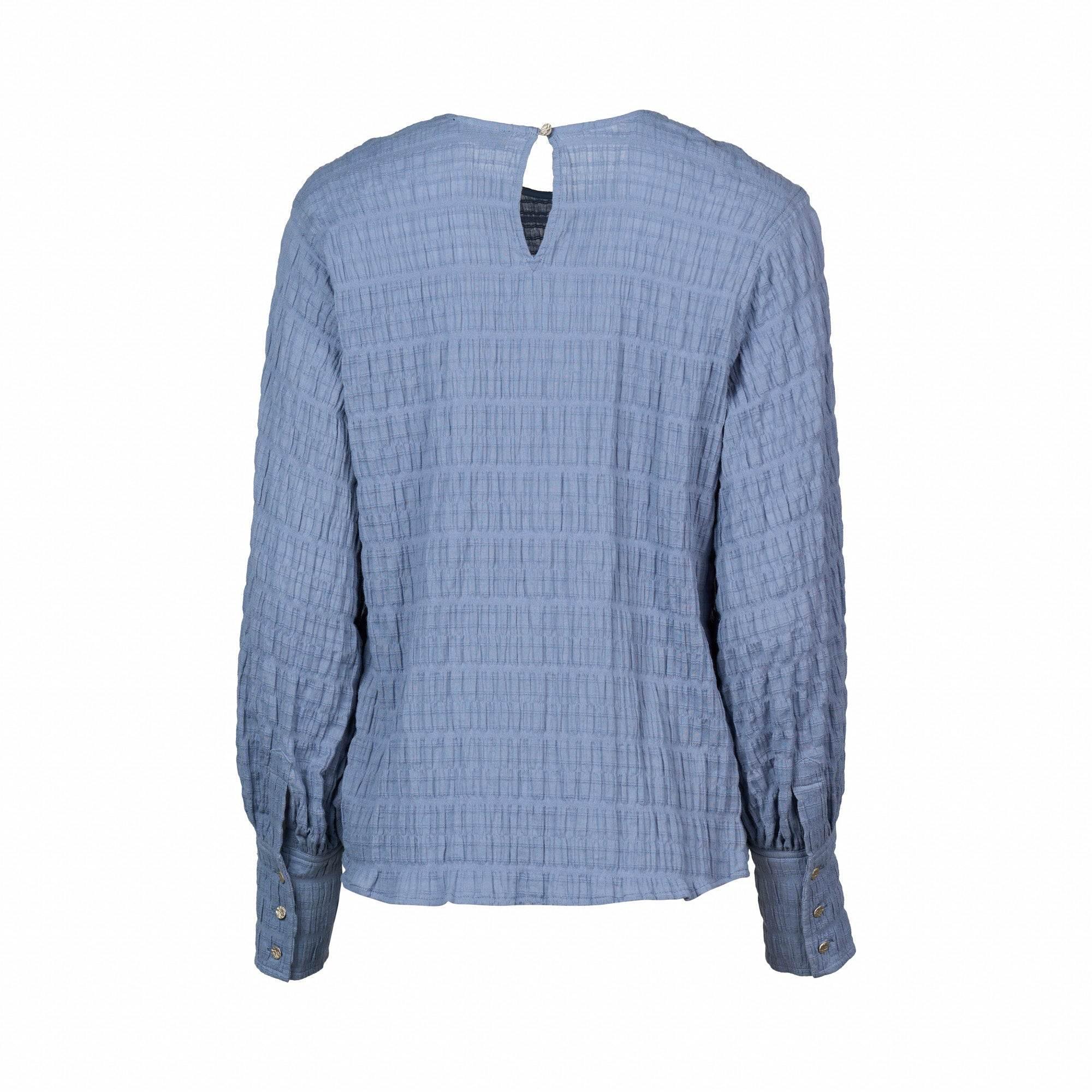 Back view of a textured denim blue long sleeve blouse with buttoned cuffs