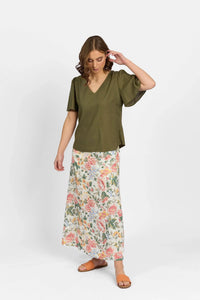 Woman wearing olive green V-neck short sleeve top with floral maxi skirt and sandals