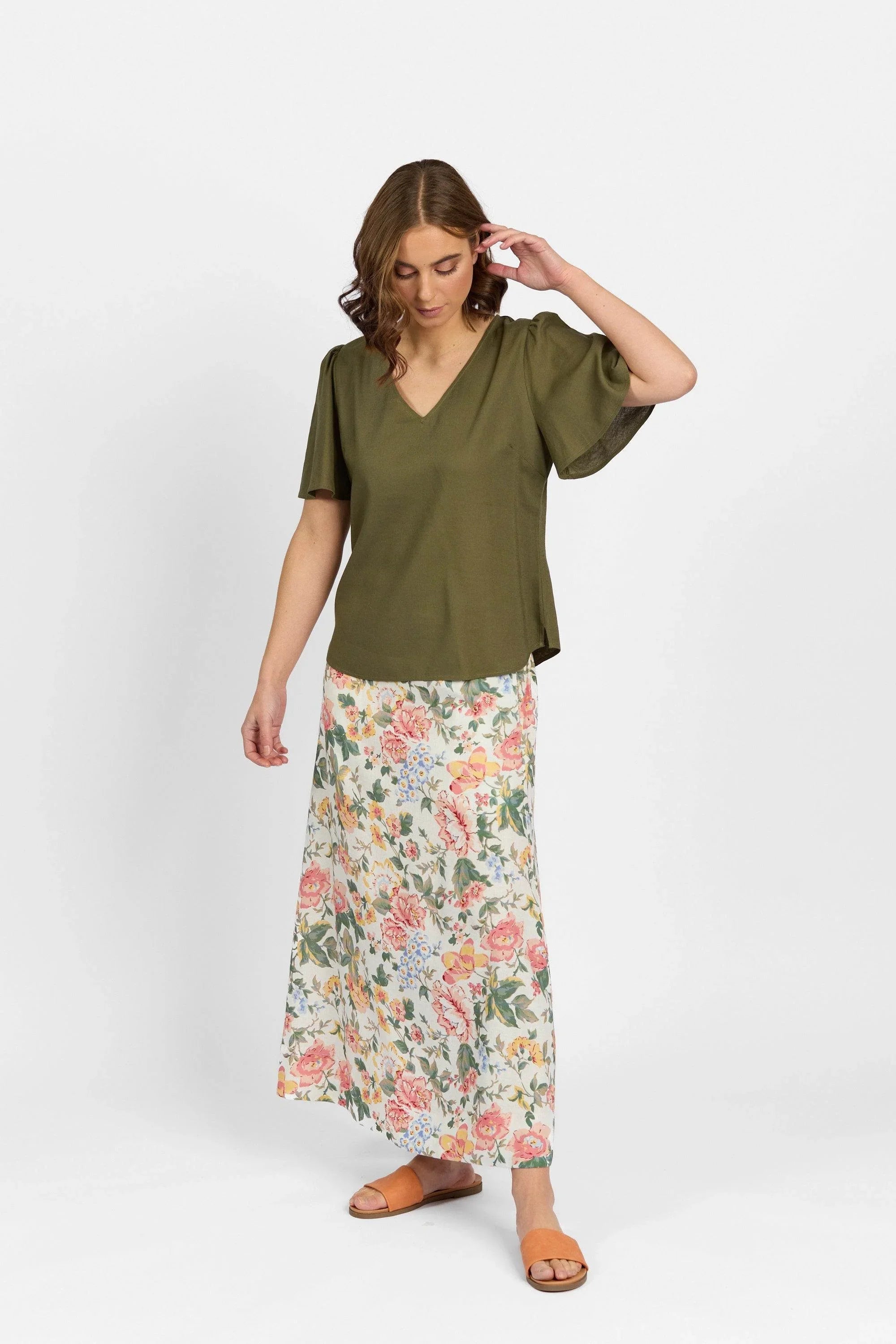 Woman wearing olive green V-neck short sleeve top with floral maxi skirt and sandals