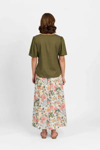 Woman modeling olive green short sleeve top and floral print maxi skirt, back view