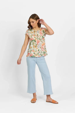 Woman wearing a floral short sleeve blouse with light blue wide-leg jeans and orange sandals