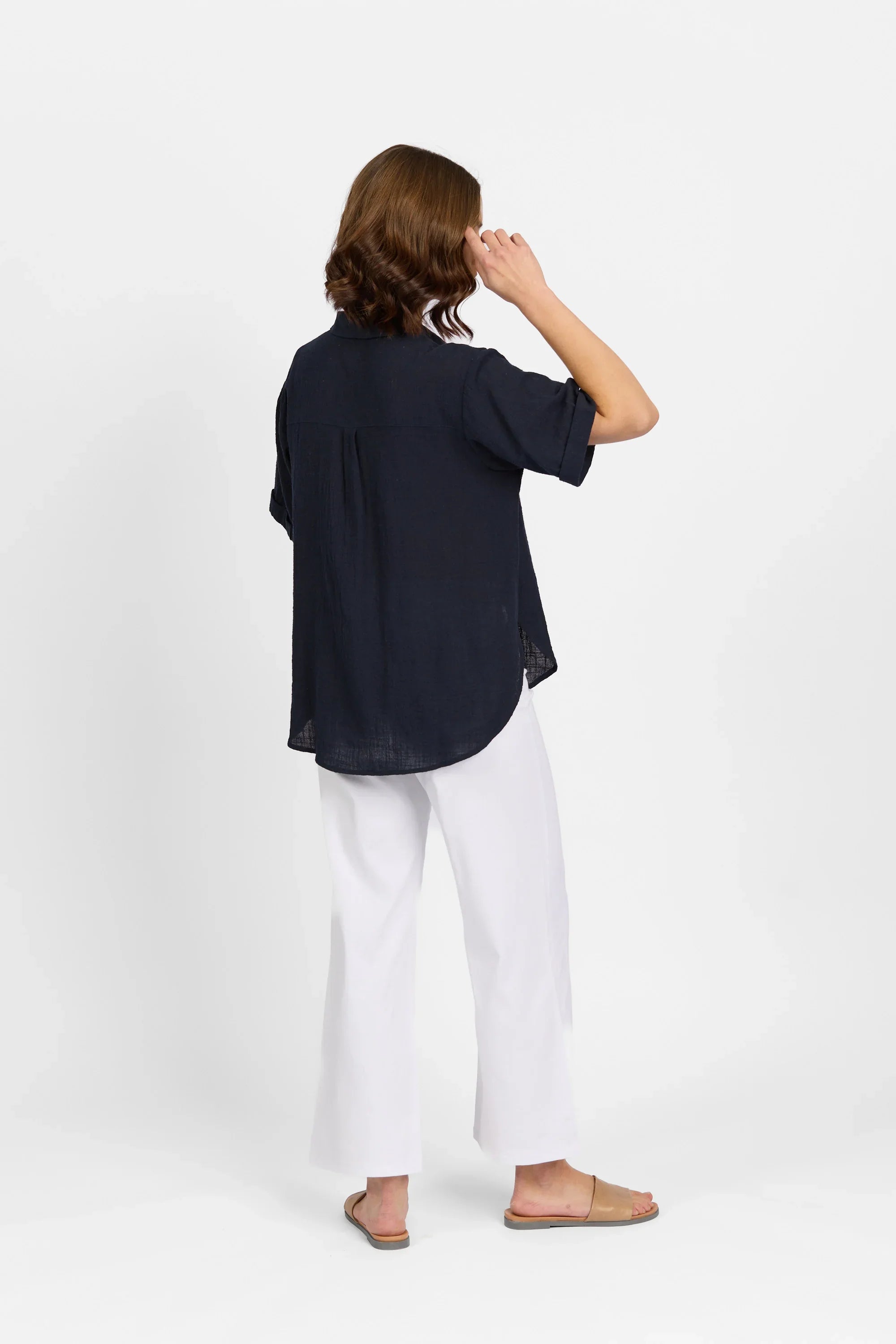 Woman modeling navy short sleeve shirt and white wide-leg pants, back view