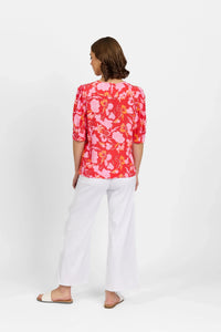 Woman wearing a pink floral blouse with puff sleeves and white wide-leg pants, back view