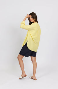 Woman wearing a yellow striped long sleeve shirt and navy shorts, side view