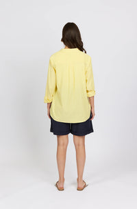 Back view of a woman in a yellow striped shirt and black shorts with sandals