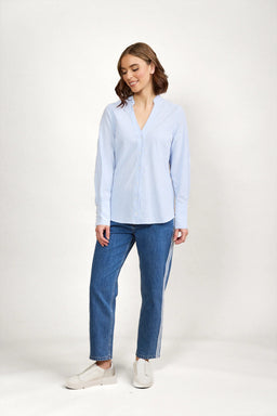 Woman wearing blue and white striped button-up shirt, jeans, and white sneakers