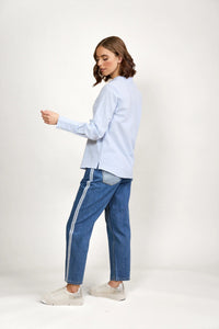 Woman wearing a blue and white striped long sleeve shirt and blue jeans with side stripes