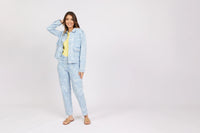 Woman modeling light blue denim jacket and jeans with white heart patterns, yellow top, sandals