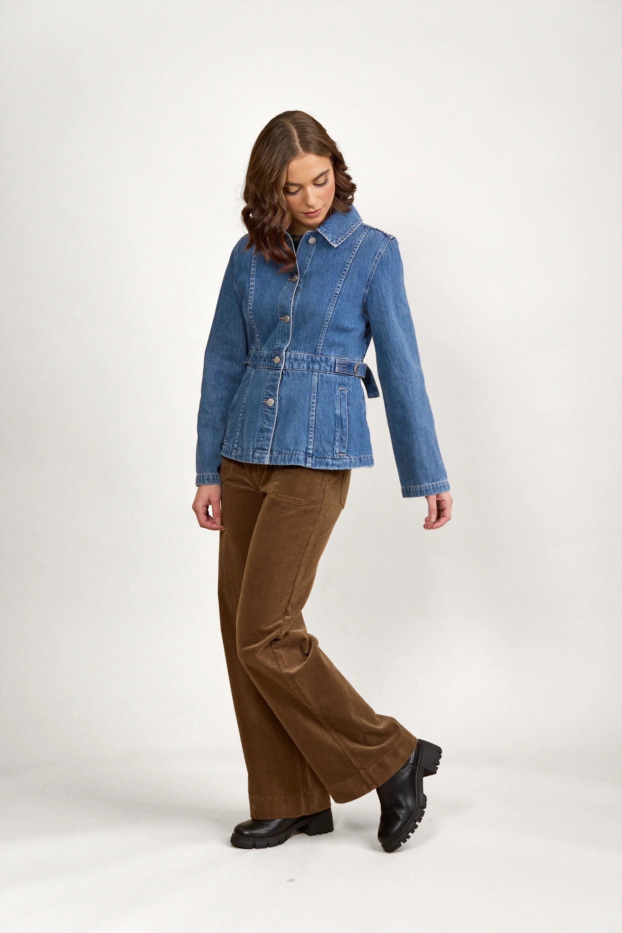 Woman wearing a fitted blue denim jacket with brown corduroy pants and black boots