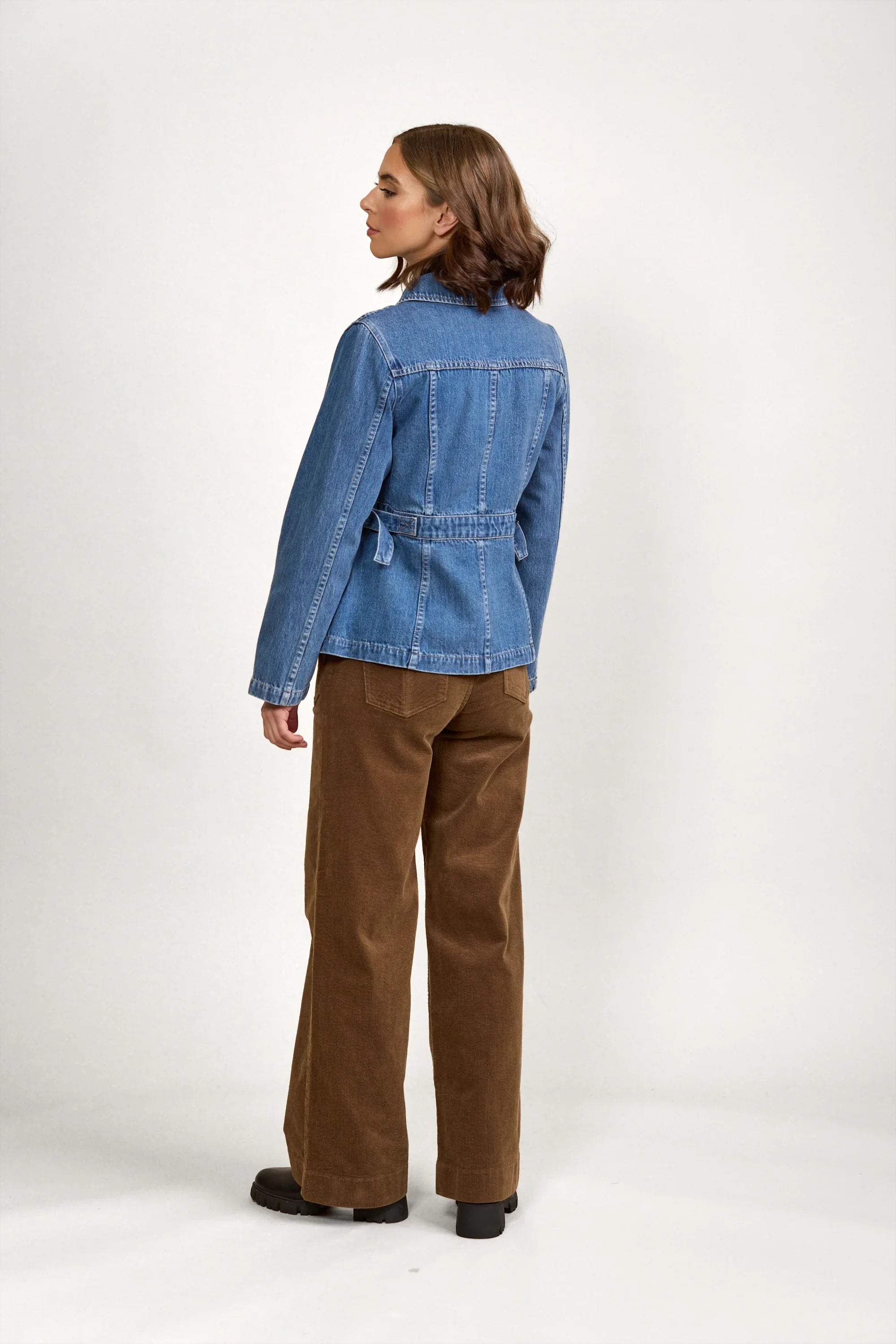 Woman wearing a blue denim jacket and brown wide-leg pants, shown from the back