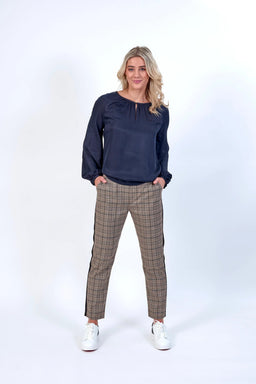 Woman wearing black blouse and plaid check pants with white sneakers on white background