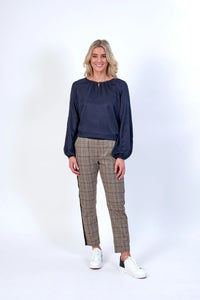 Woman wearing navy long sleeve blouse and tan plaid pants with white sneakers