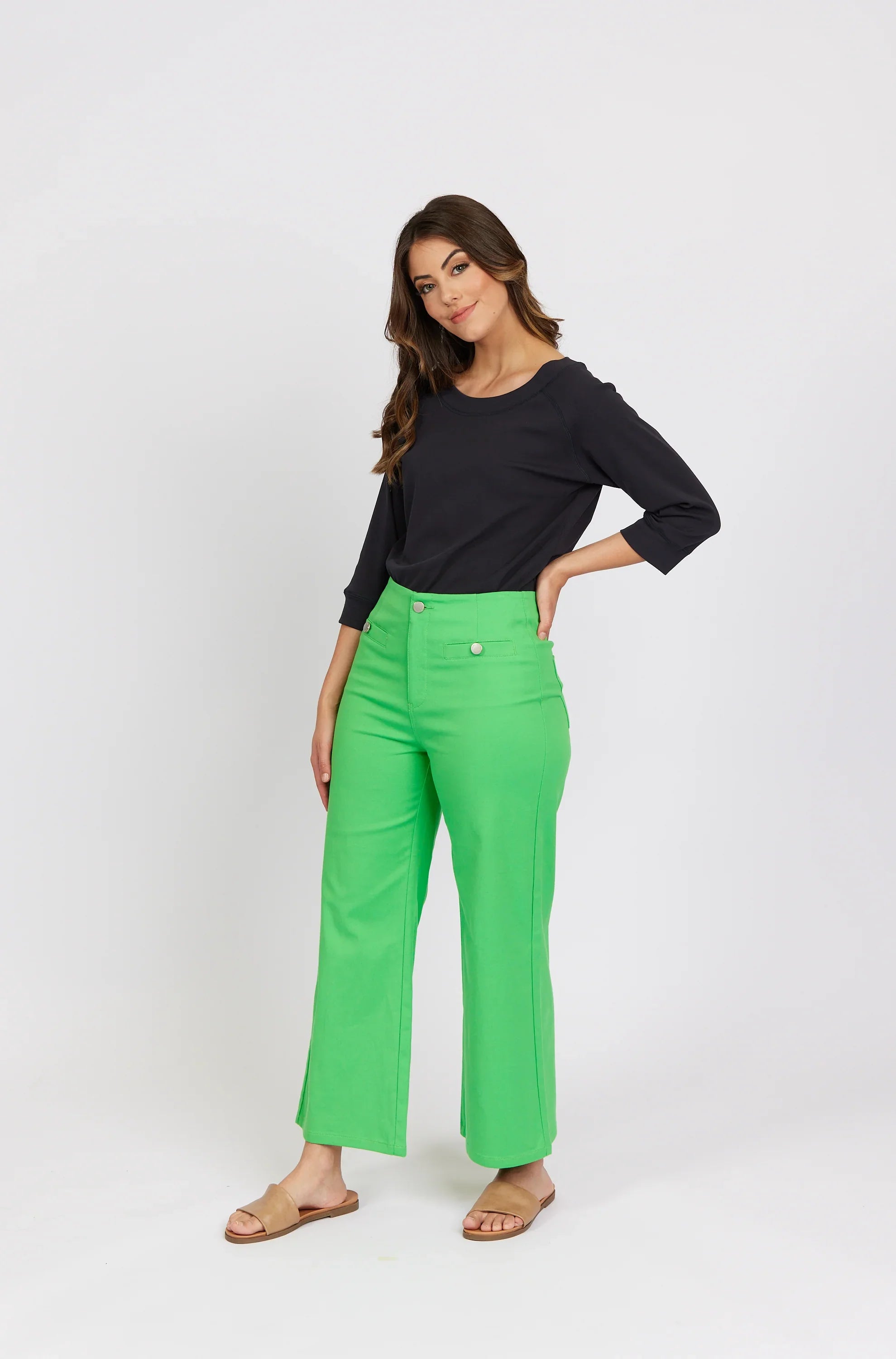 Woman wearing bright green high-waisted wide leg jeans and a black long sleeve top