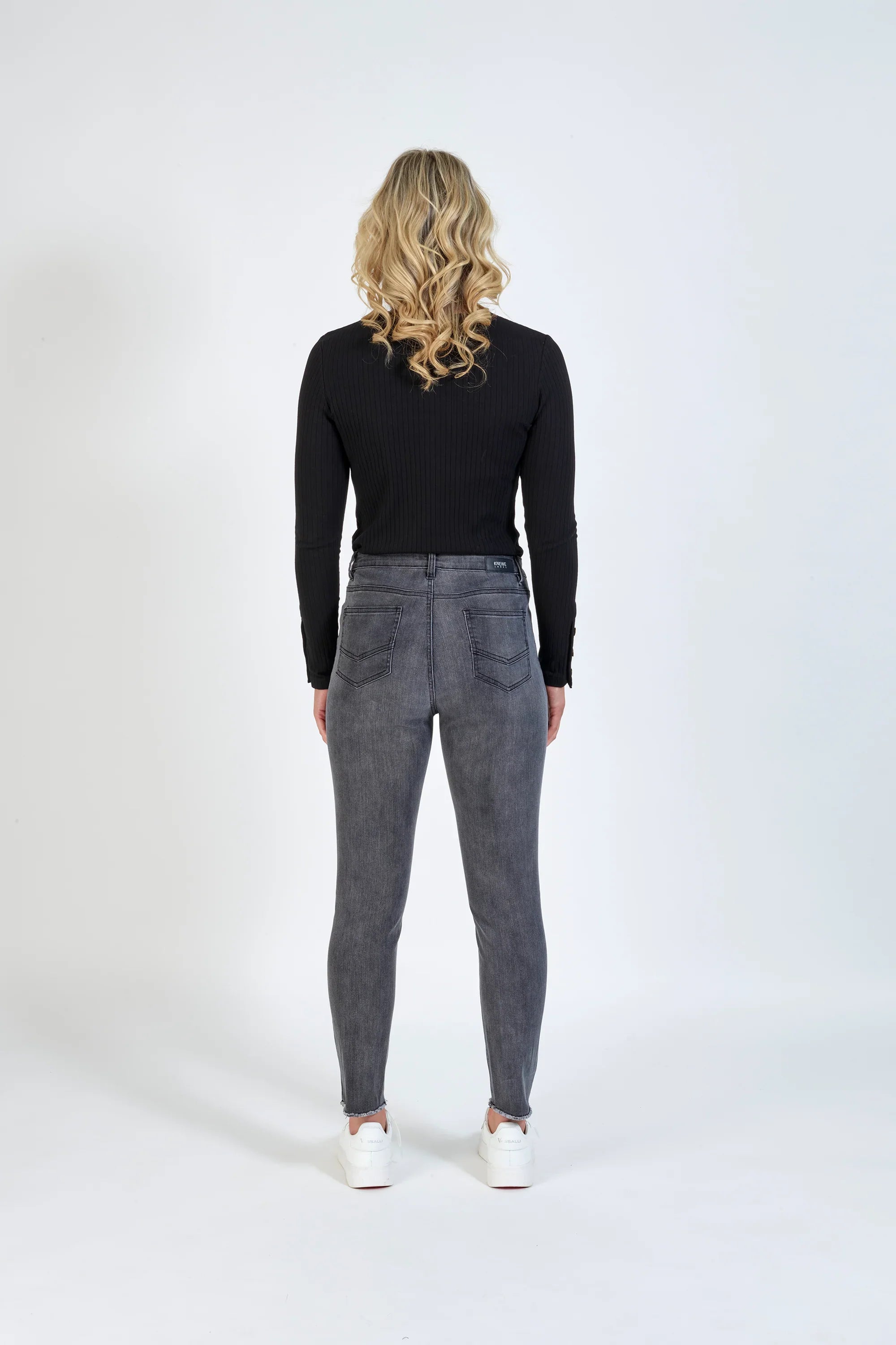 Woman wearing space grey skinny jeans and black ribbed long sleeve top, back view