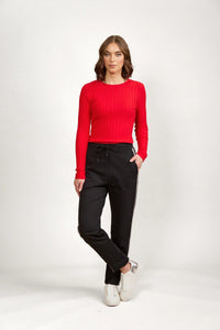 Woman in black drawstring pants with white side stripes, red ribbed top, and white sneakers