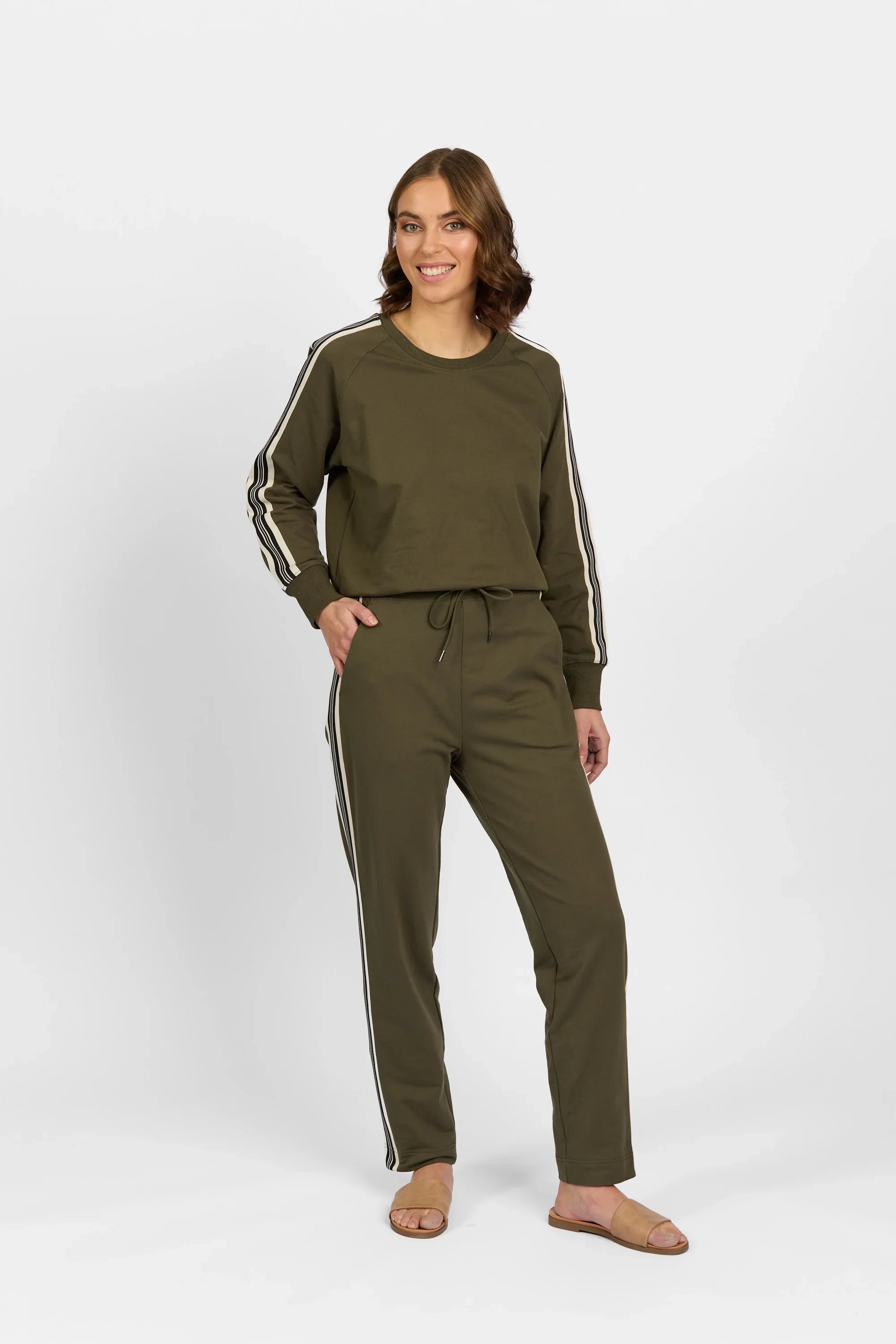 Woman wearing khaki pants and matching long-sleeve top with side stripes on white background