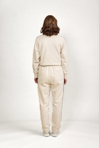 Back view of woman wearing stone-colored jogger pants and sweatshirt with black side piping