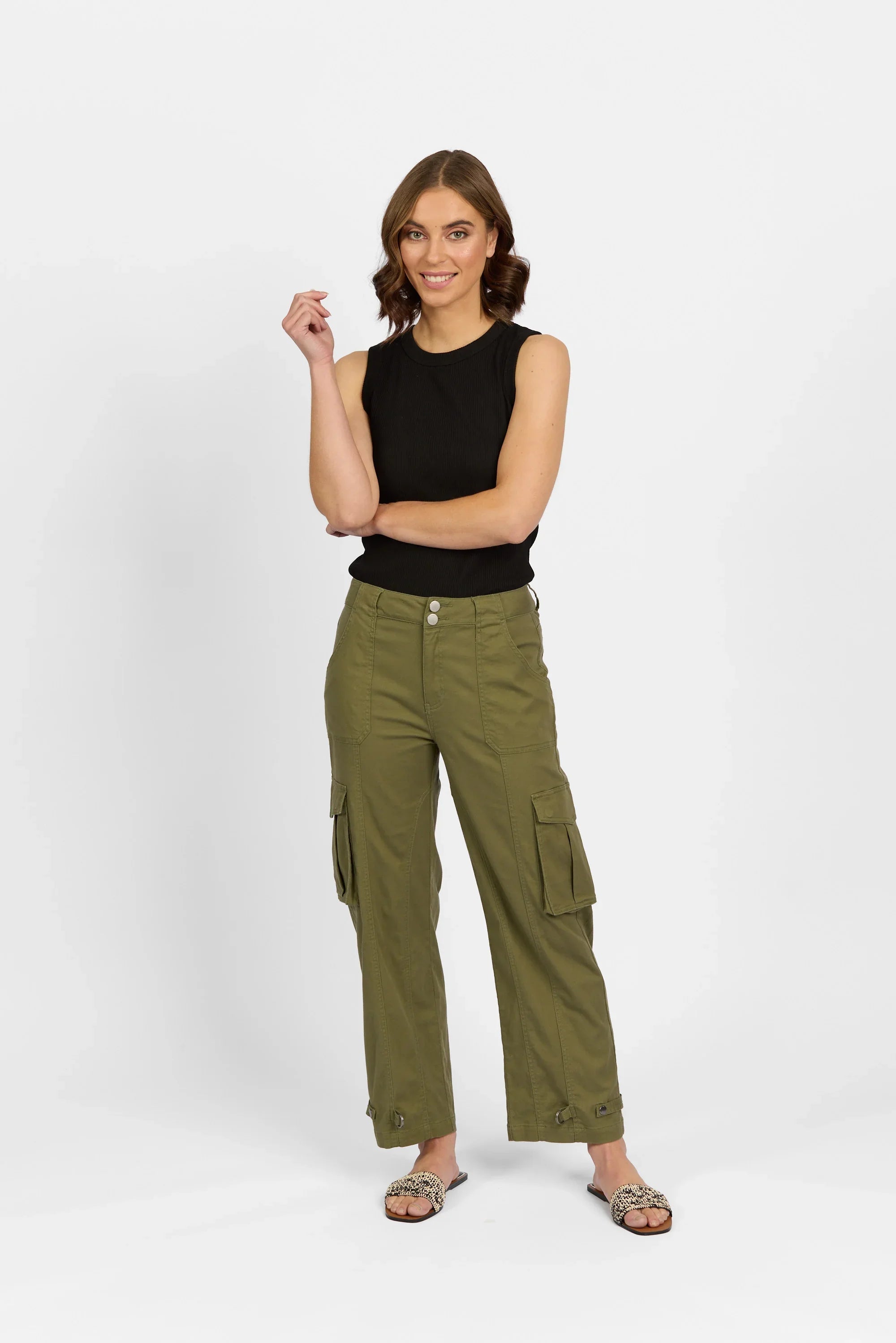 Woman wearing khaki cargo pants and a black sleeveless top, posing against a white background.