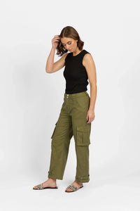 Woman in sleeveless black top and khaki cargo pants with side pockets, standing studio pose