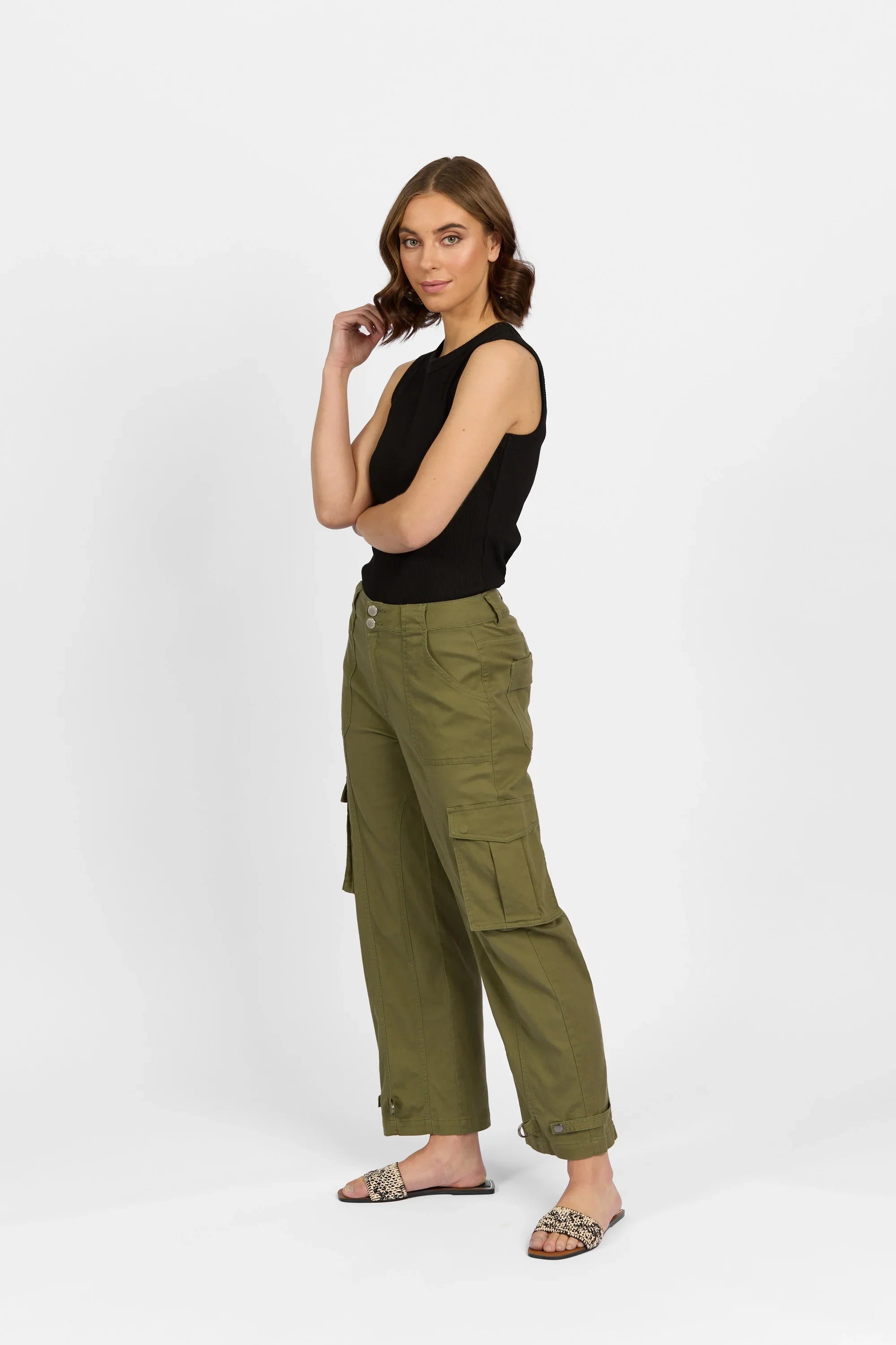Woman in sleeveless black top and khaki green cargo pants on white background