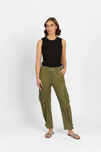 Woman wearing sleeveless black top and khaki cargo pants with side pockets, standing indoors.