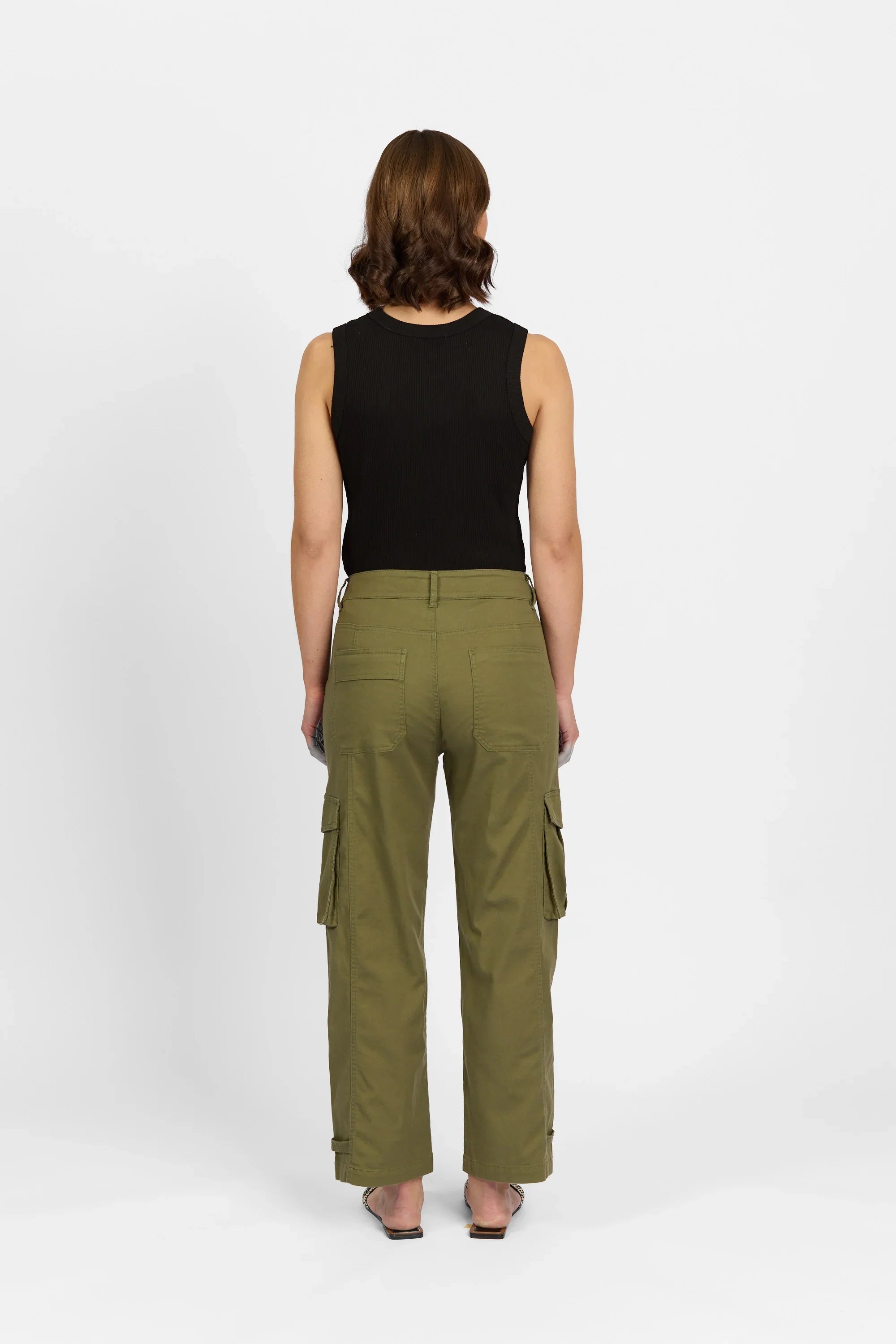 Woman wearing olive green cargo pants with back pockets and a black sleeveless top, rear view
