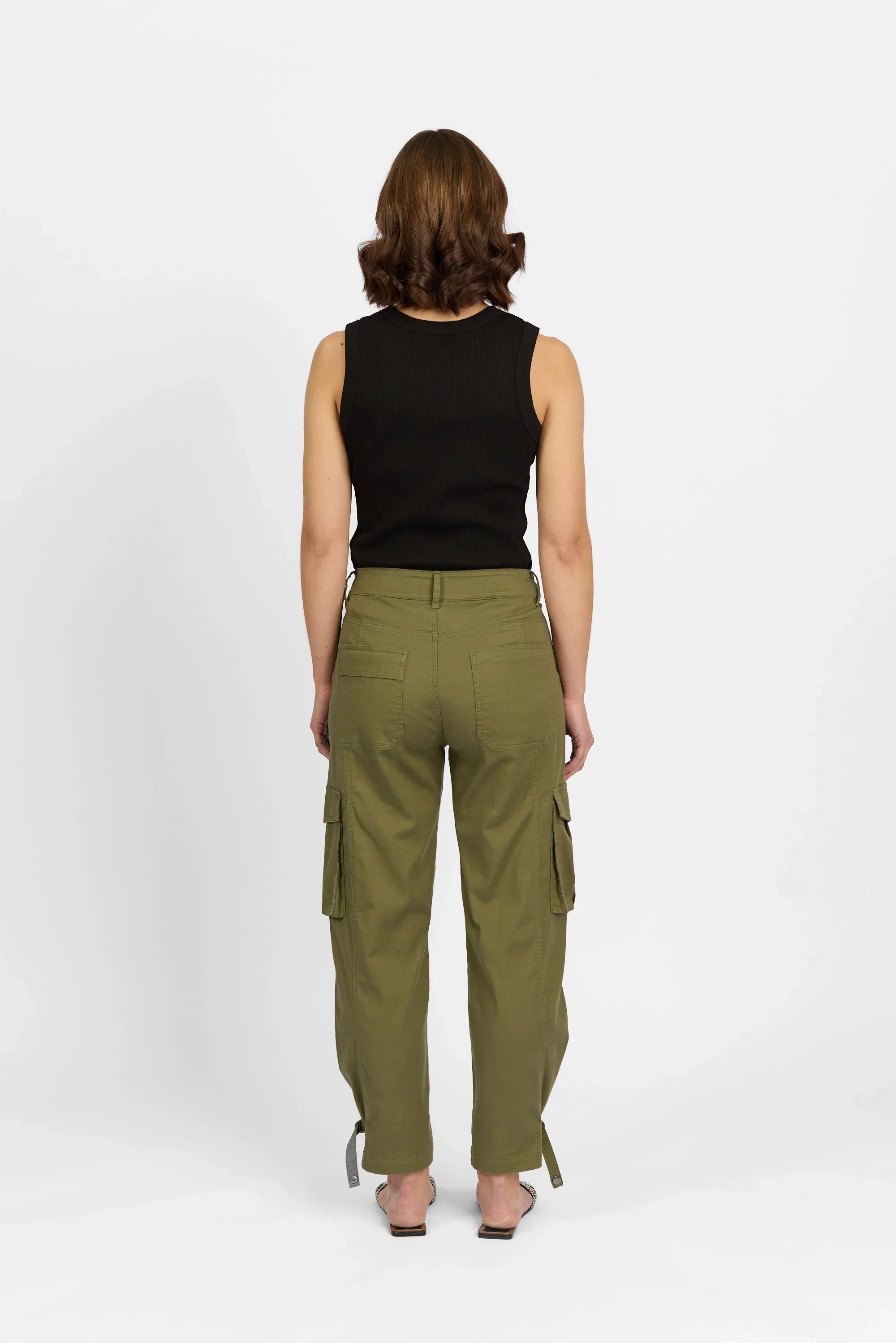 Woman wearing khaki cargo pants with side pockets, black sleeveless top, rear view