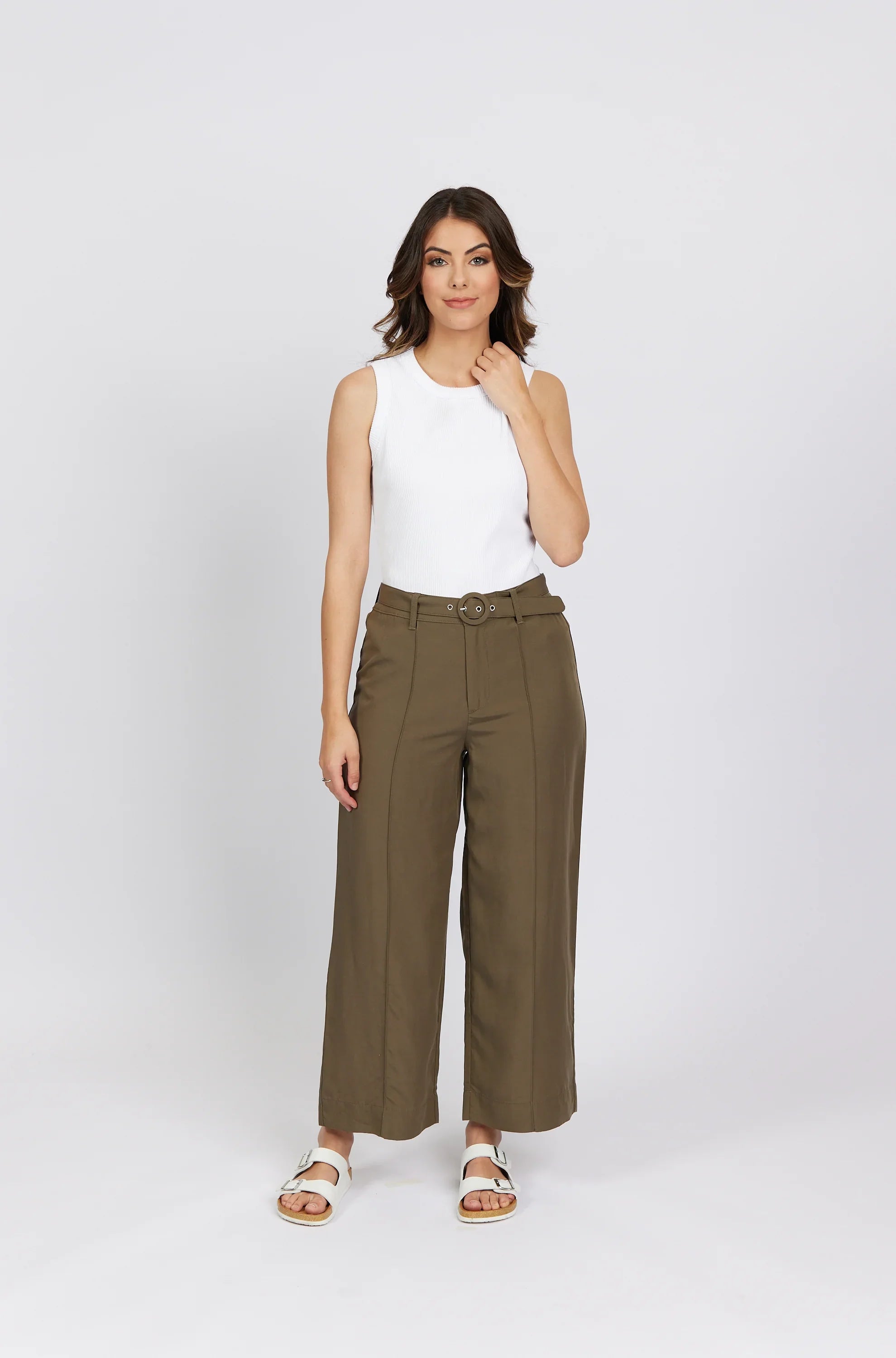Woman in wide-leg khaki pants with belt, white sleeveless top, and white sandals