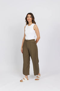 Woman in khaki wide-leg pants with belt and white sleeveless top on plain background