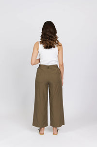Woman in white tank top and wide leg khaki pants, back view, standing against white background