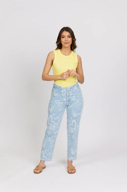 Woman wearing light blue heart print jeans, yellow sleeveless top, and tan sandals