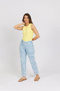 Woman wearing light blue heart print jeans, yellow sleeveless top, brown sandals