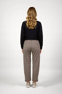 Woman wearing checkered straight-leg pants and black sweater, back view, studio setting