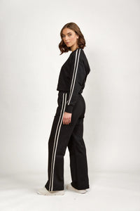 Woman wearing black wide-leg pants and matching top with white side stripes, casual outfit