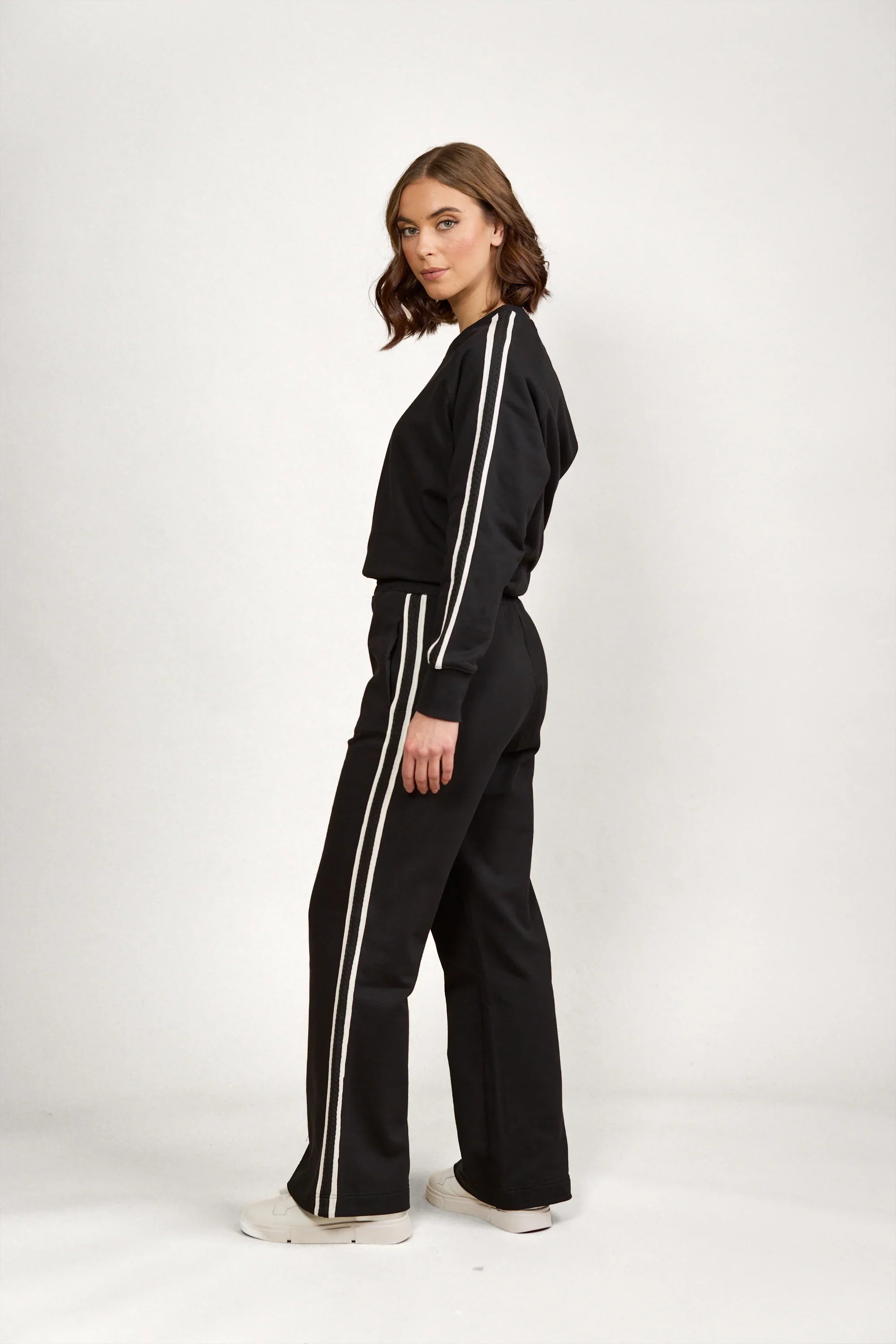 Woman wearing black wide-leg pants and matching top with white side stripes, casual outfit