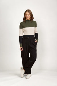 Woman wearing black cargo pants with utility pockets and a colorblock knit top, standing in studio
