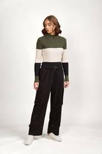 Woman wearing high-waisted black cargo pants and colorblock knit sweater in studio