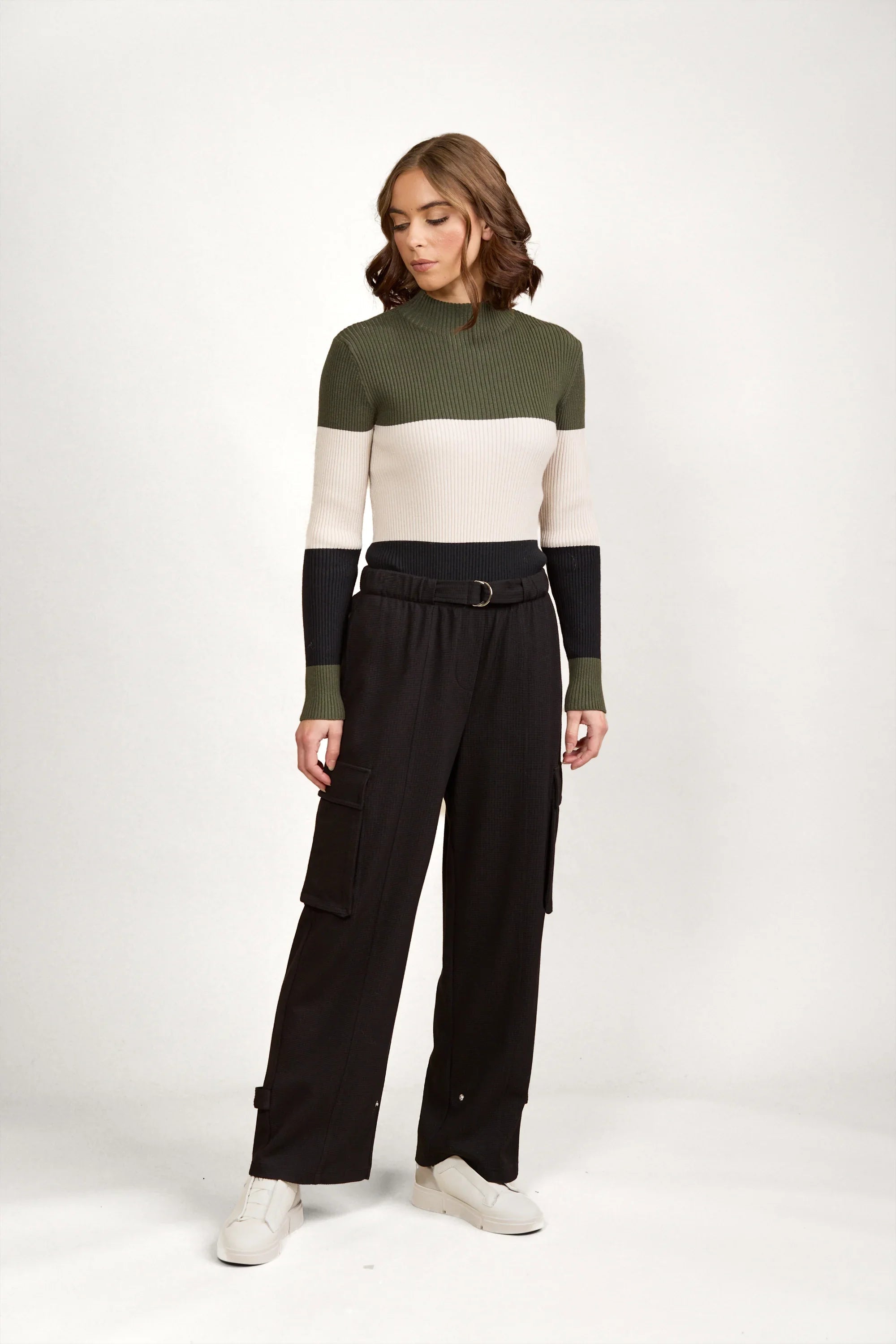 Woman wearing high-waisted black cargo pants and colorblock knit sweater in studio