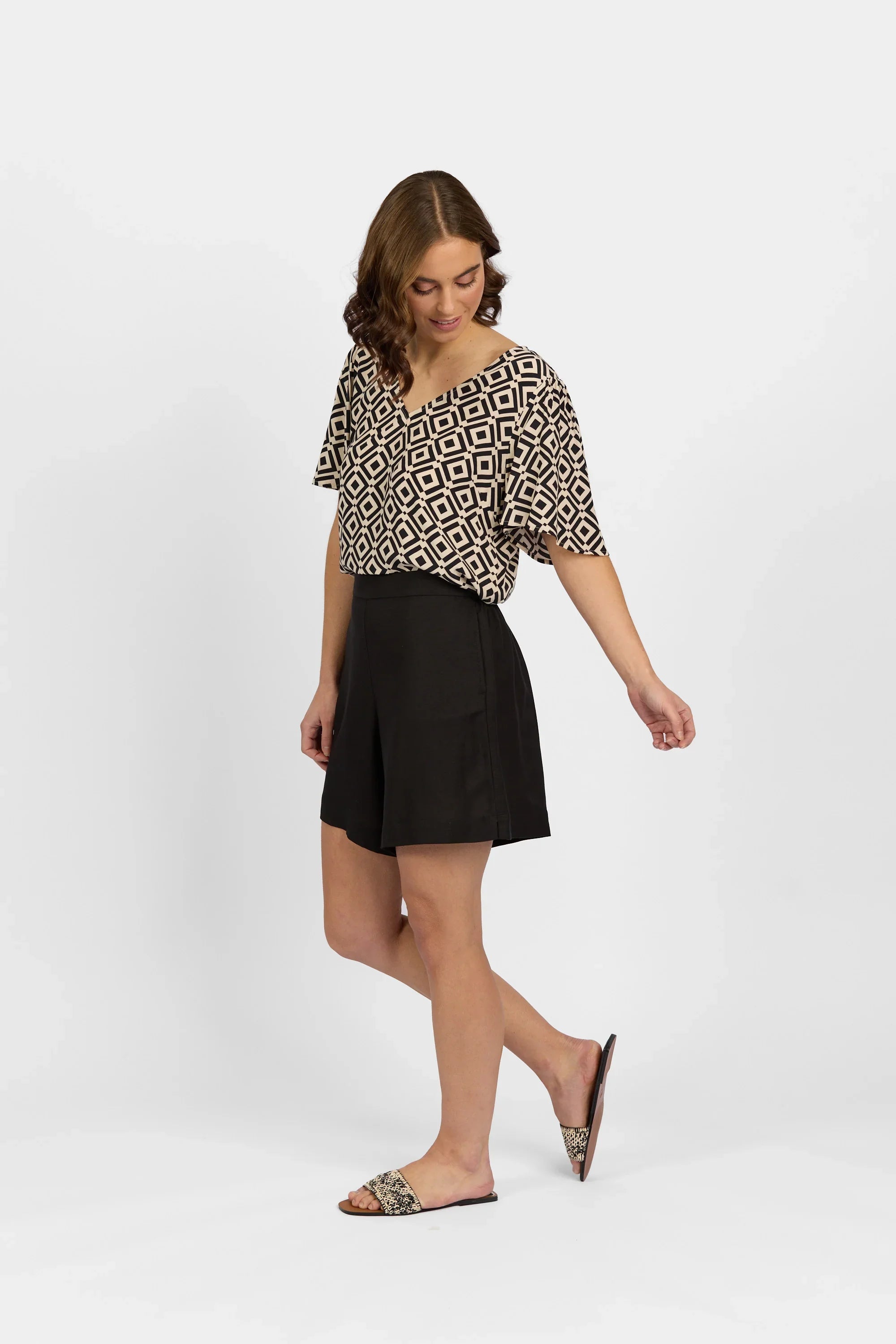 Woman wearing black high-waisted shorts and printed top, contemporary fashion style