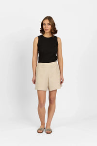 Woman wearing ecru tailored shorts with sleeveless black top and patterned sandals