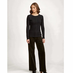 Woman wearing black long sleeve top and dark wide leg pants, studio background