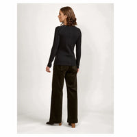 Woman in black long-sleeve top and wide-leg dark pants, shown from the back, studio setting