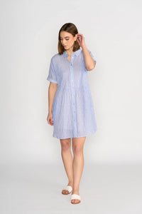 Woman wearing a short-sleeve blue striped button-up cocoon dress, standing indoors.