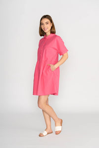 Woman modeling short-sleeve raspberry cocoon dress with pockets and white sandals
