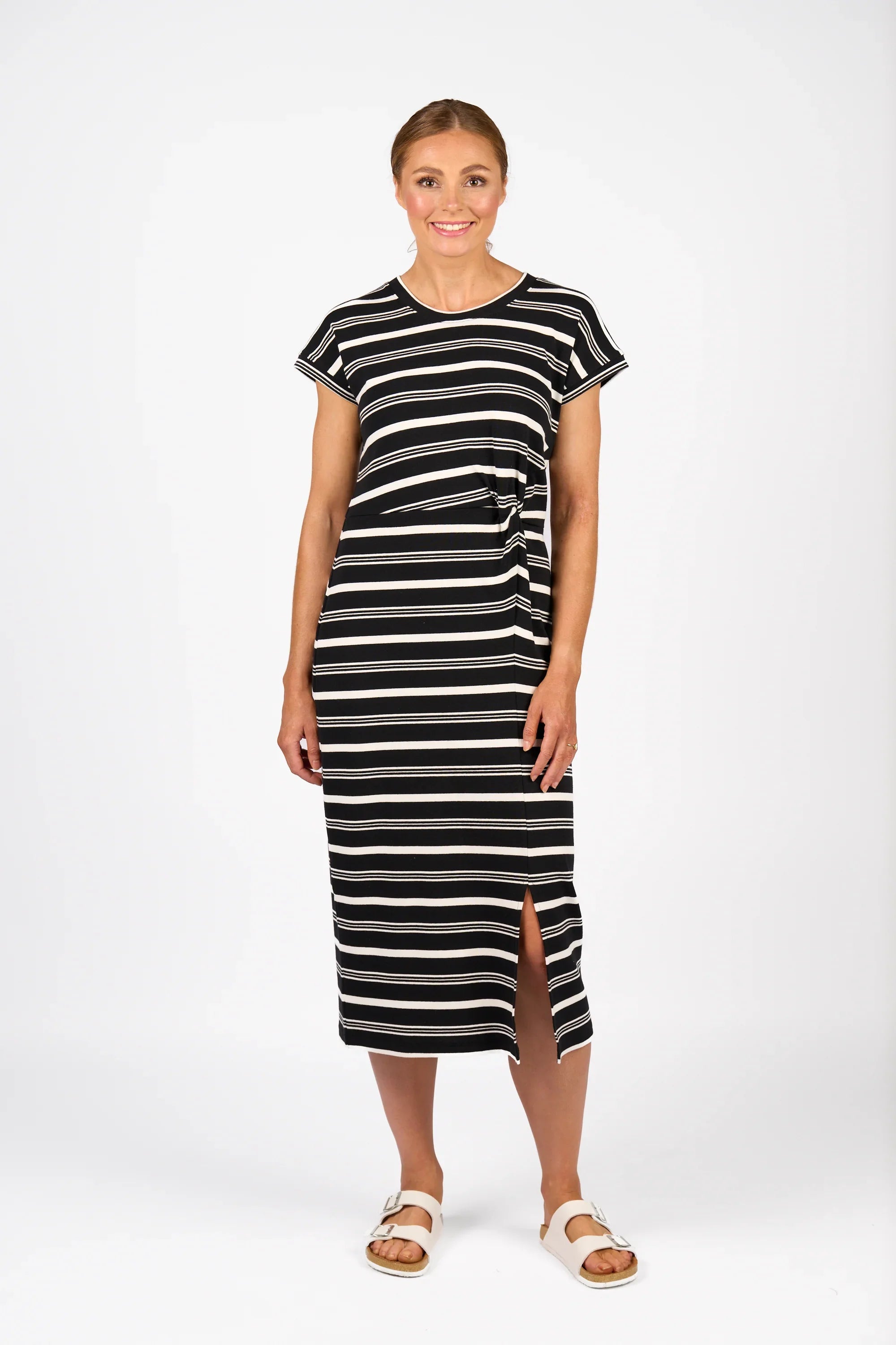 Woman wearing a black and white striped midi dress with short sleeves and front slit