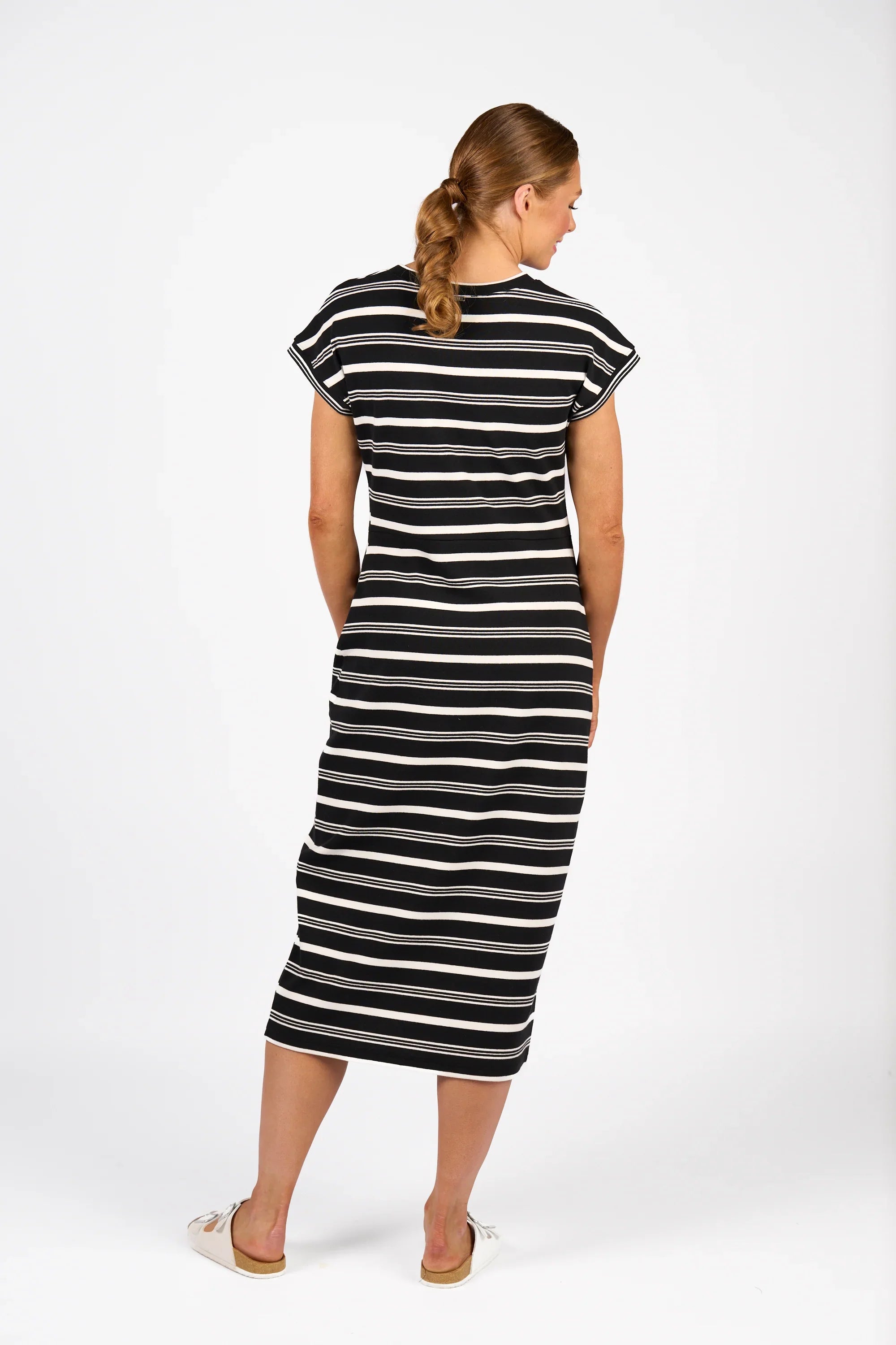 Woman wearing a black and white striped midi dress with short sleeves, back view
