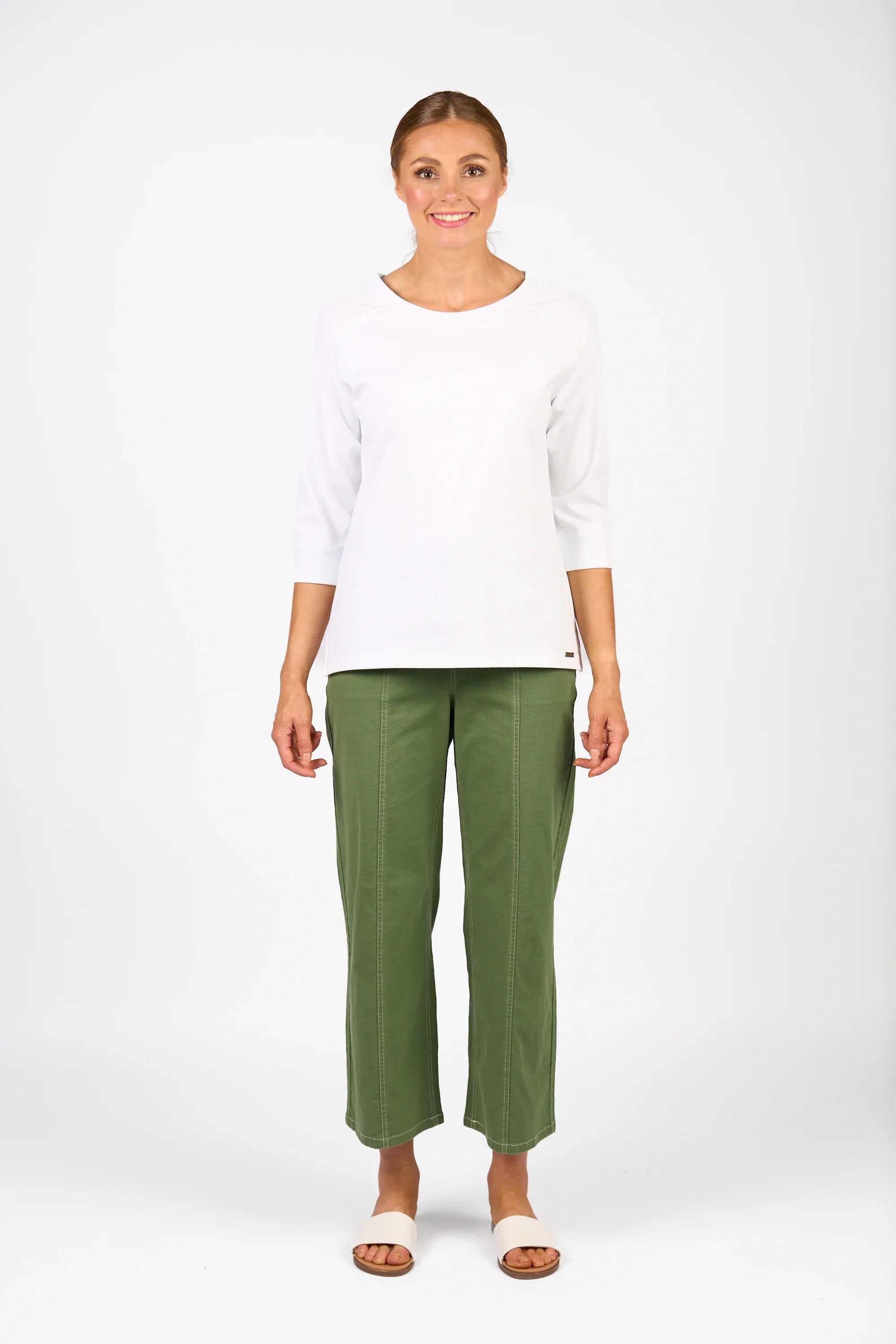 Woman wearing a white 3/4 sleeve top and olive green wide-leg pants, standing in studio.