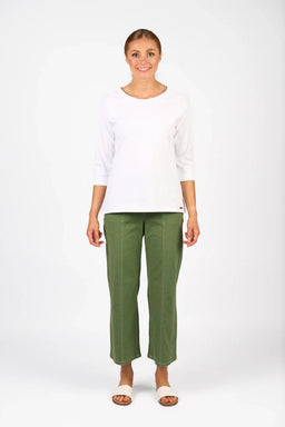 Woman wearing a white 3/4 sleeve top and olive green wide-leg pants, standing in studio.